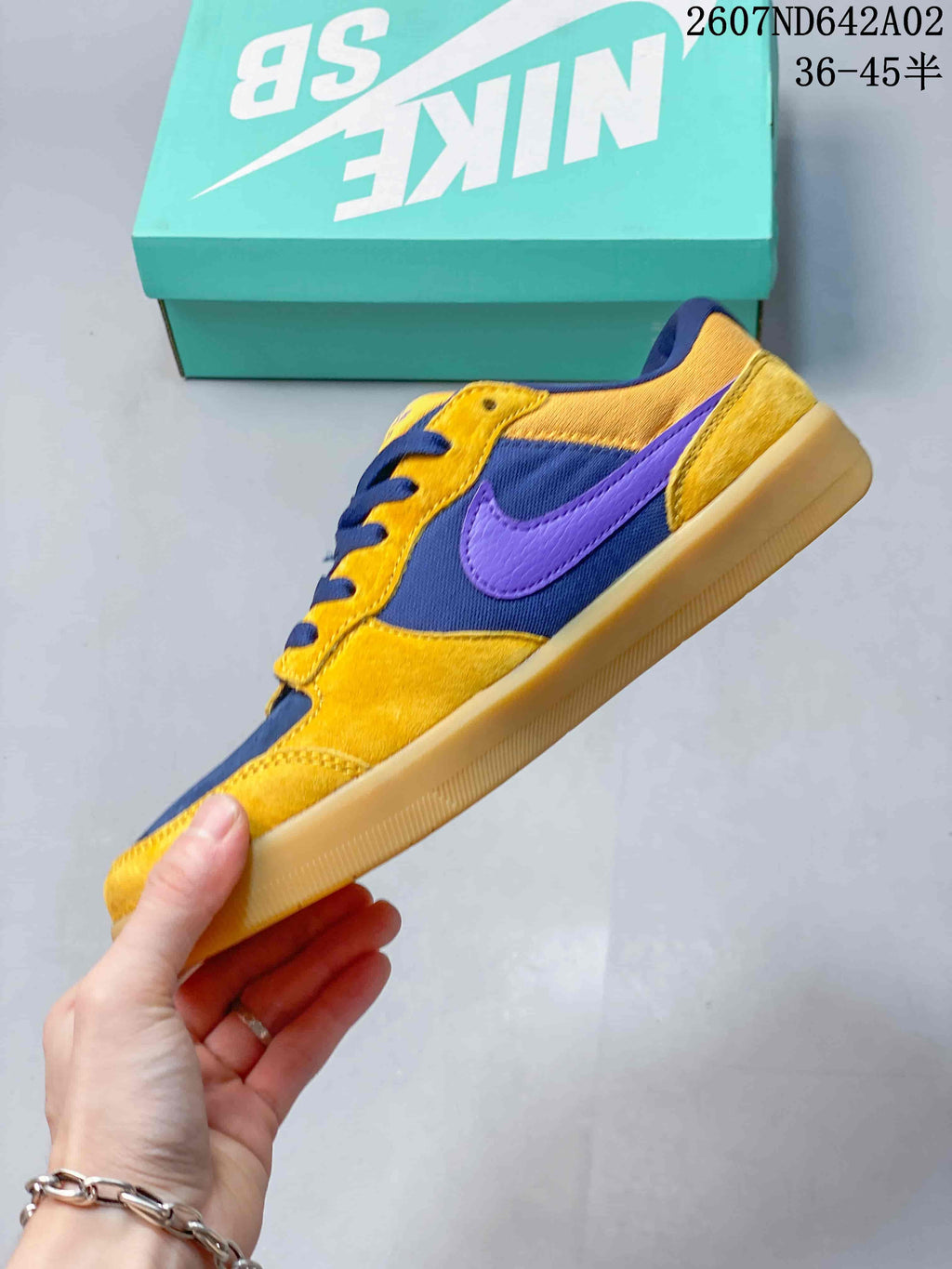 Side view showing yellow and navy panels, a purple side logo, and a gum-colored sole