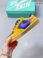 Side view showing yellow and navy panels, a purple side logo, and a gum-colored sole