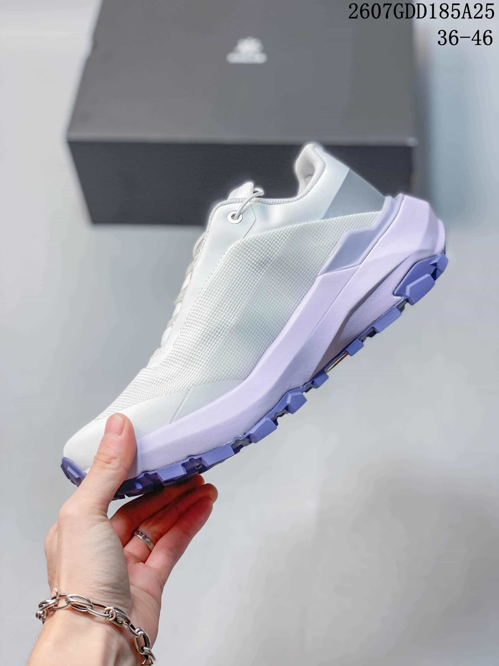 Side view of the white low-top shoe showing textured upper panels, lilac midsole accents, and a lugged outsole; overlay shows style code 2607GDD185A25 and size range 36–46.