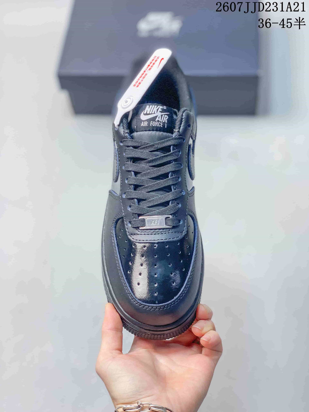 Top view of a black sneaker showing the laces, perforated toe box, tongue branding and metal lace detail.