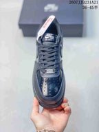 Top view of a black sneaker showing the laces, perforated toe box, tongue branding and metal lace detail.