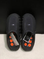 Top view of the black slides showing textured footbeds, orange circular outsole elements, and product inserts.
