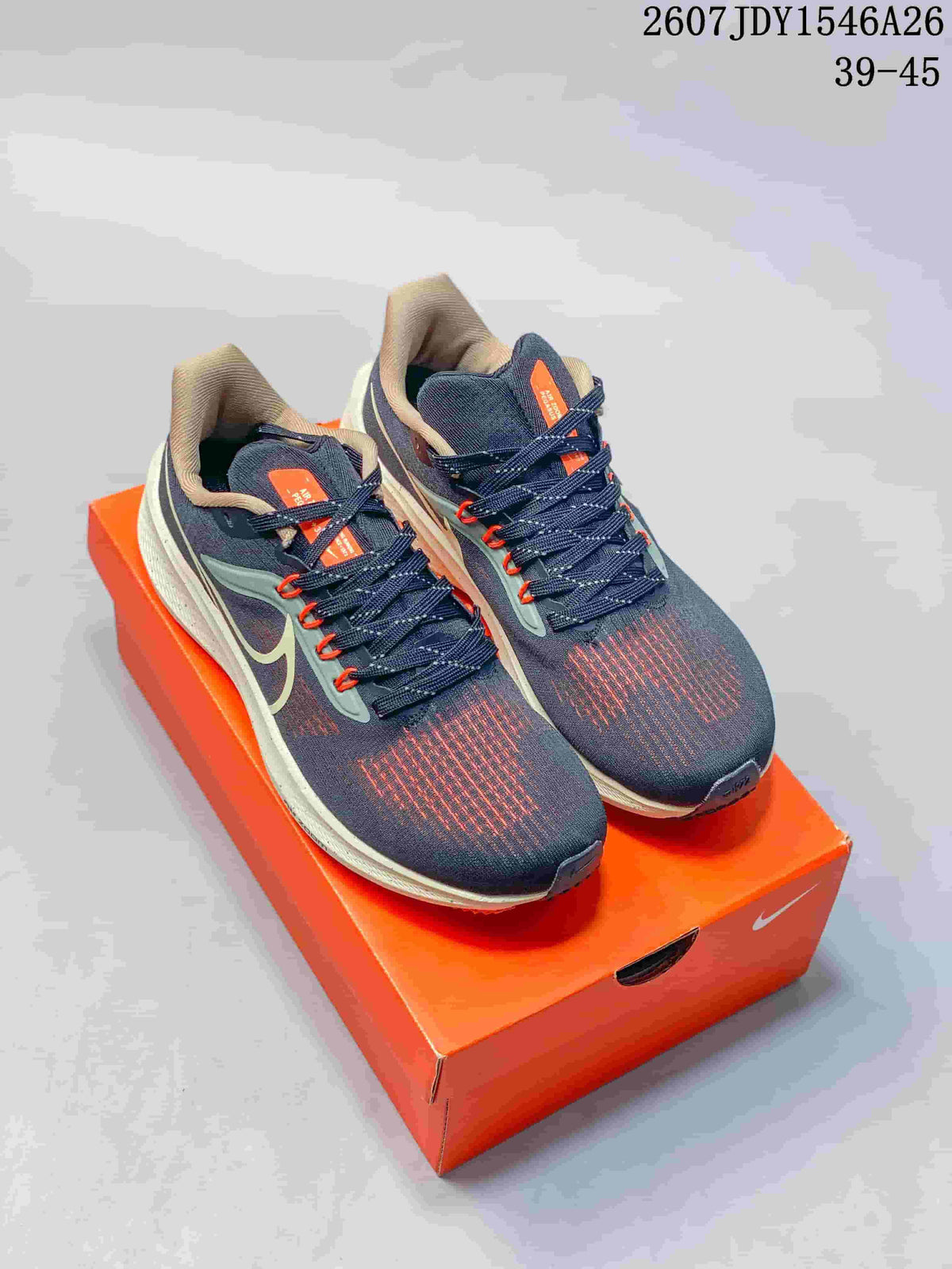 Pair of navy Nike Air Zoom Pegasus 39 sneakers with orange accents displayed on an orange shoebox; visible text reads JDY1546A26 and 39–45.