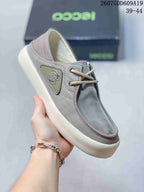 Angled close-up of the gray ECCO sneaker showing the side emblem, lace eyelets, stitched toe panel, and thick light-colored sole.