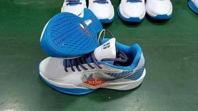 Blue and white low-top lace-up athletic sneakers, with one shoe turned over to show its patterned blue outsole.