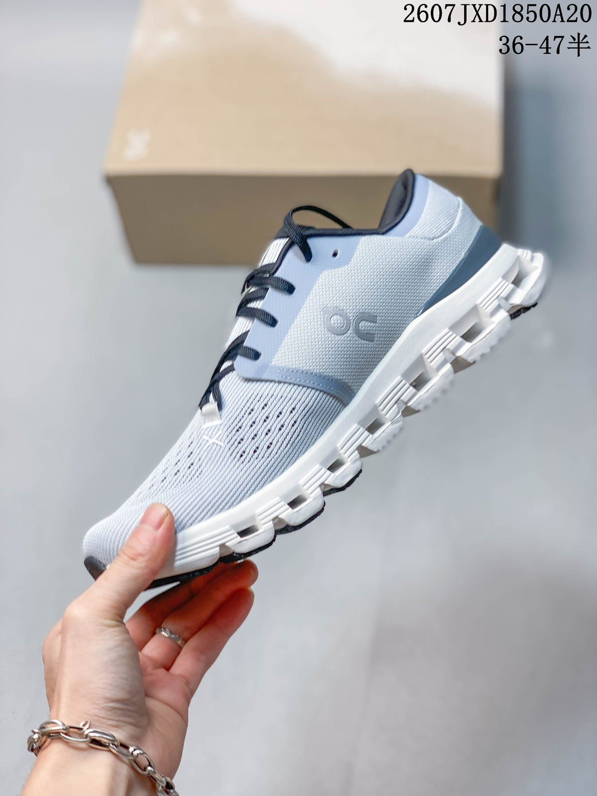 Side profile of the light gray low-top sneaker showing the knit-style upper, lace system, and segmented outsole.