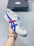 White Onitsuka Tiger slip-on sneaker with blue side stripes and red accent details.