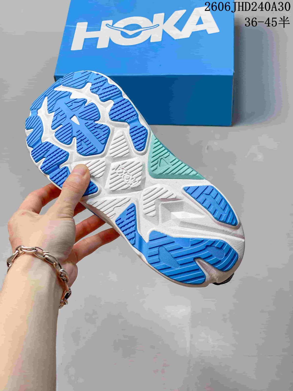 Underside of a HOKA running shoe showing a blue, white, and aqua outsole.