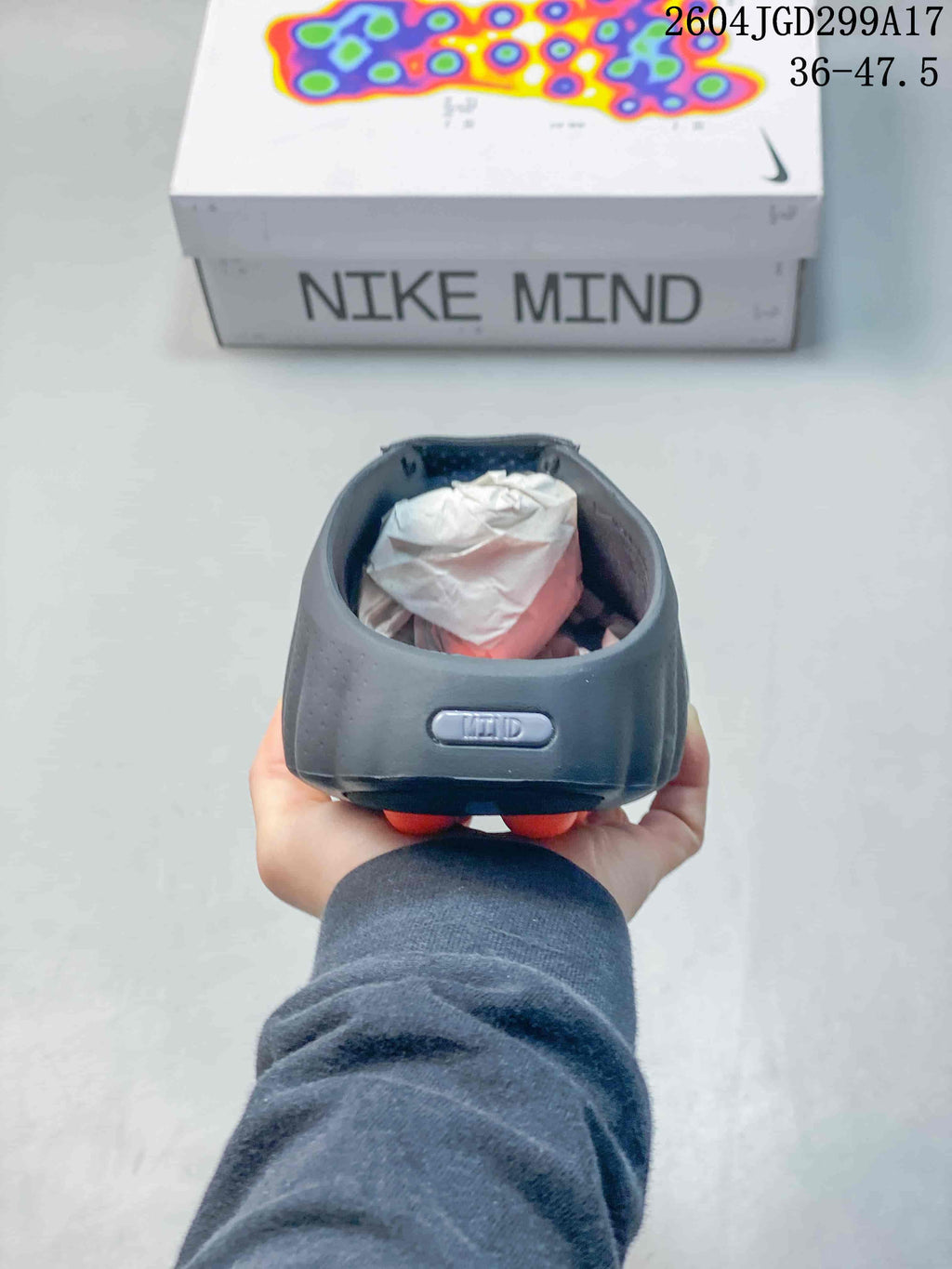 Rear view of the dark Nike Mind slide showing the padded heel area and orange outsole nodes beneath it.
