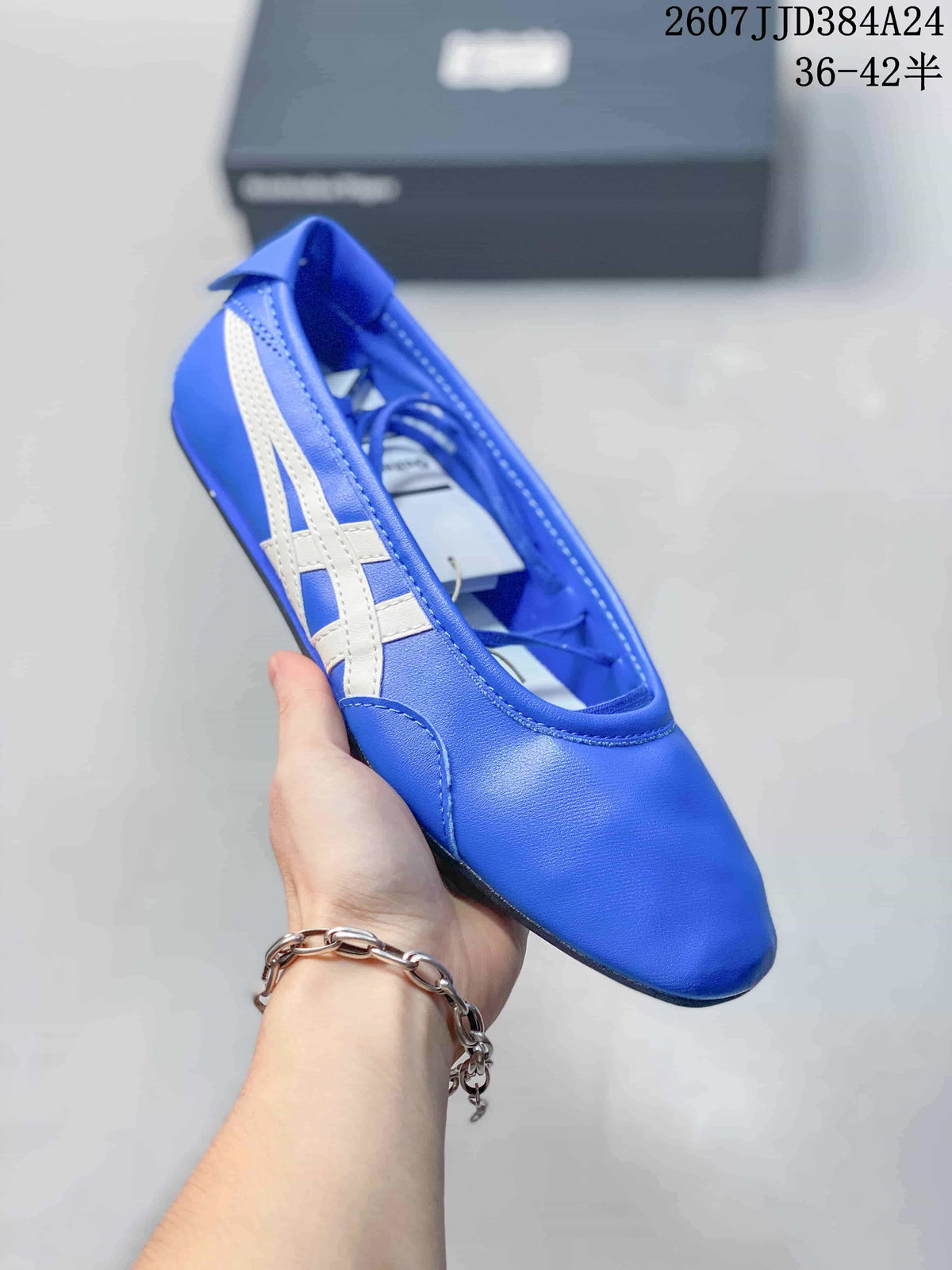 Close angled view of the blue Onitsuka Tiger shoe showing the white side stripes, rounded toe, and strap opening.