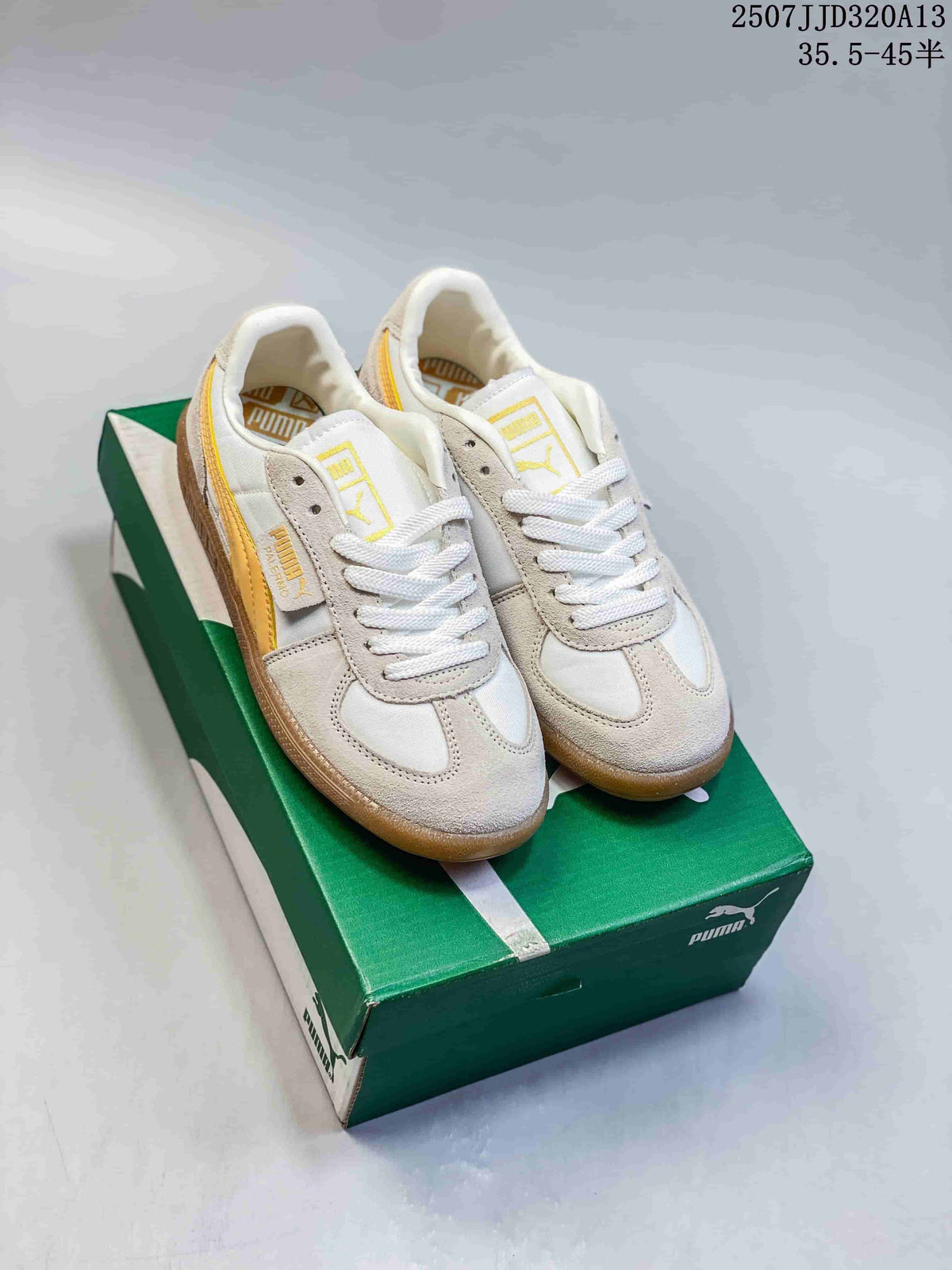 Pair of white and yellow PUMA Palermo Leather sneakers displayed on a green shoebox.