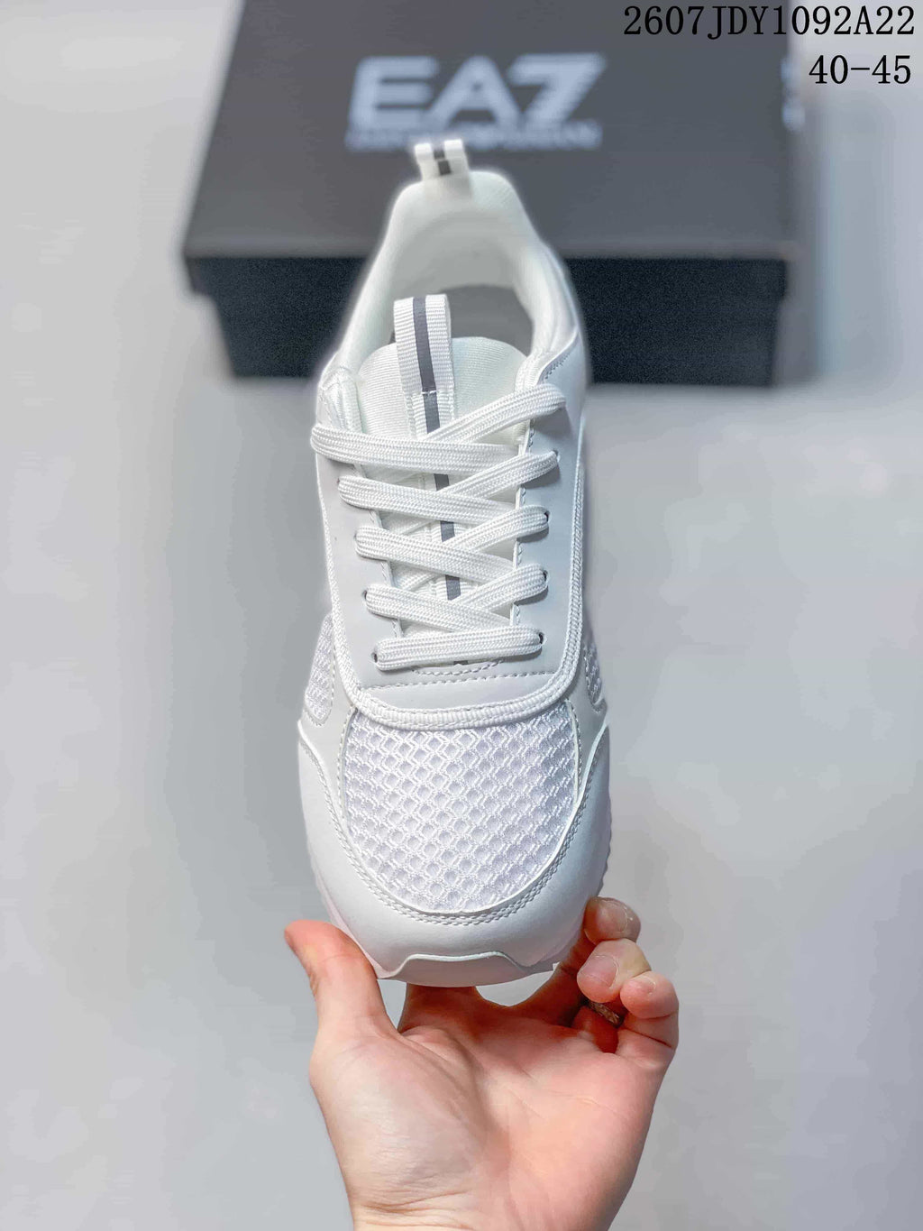 Top view of a white lace-up sneaker showing the textured mesh toe panel, padded tongue, and contrasting tongue stripe.