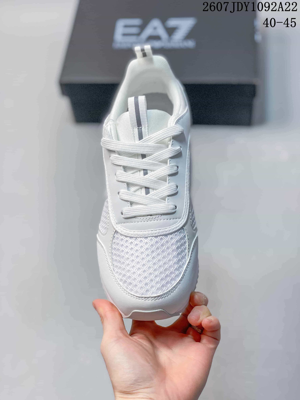 Top view of a white lace-up sneaker showing the textured mesh toe panel, padded tongue, and contrasting tongue stripe.
