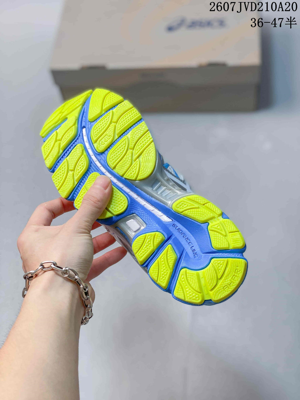 Close view of the sneaker outsole showing blue channels and lime traction sections.