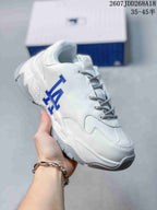 Angled side view of the white sneaker showing blue NY lettering, white panel detailing and the chunky sole.