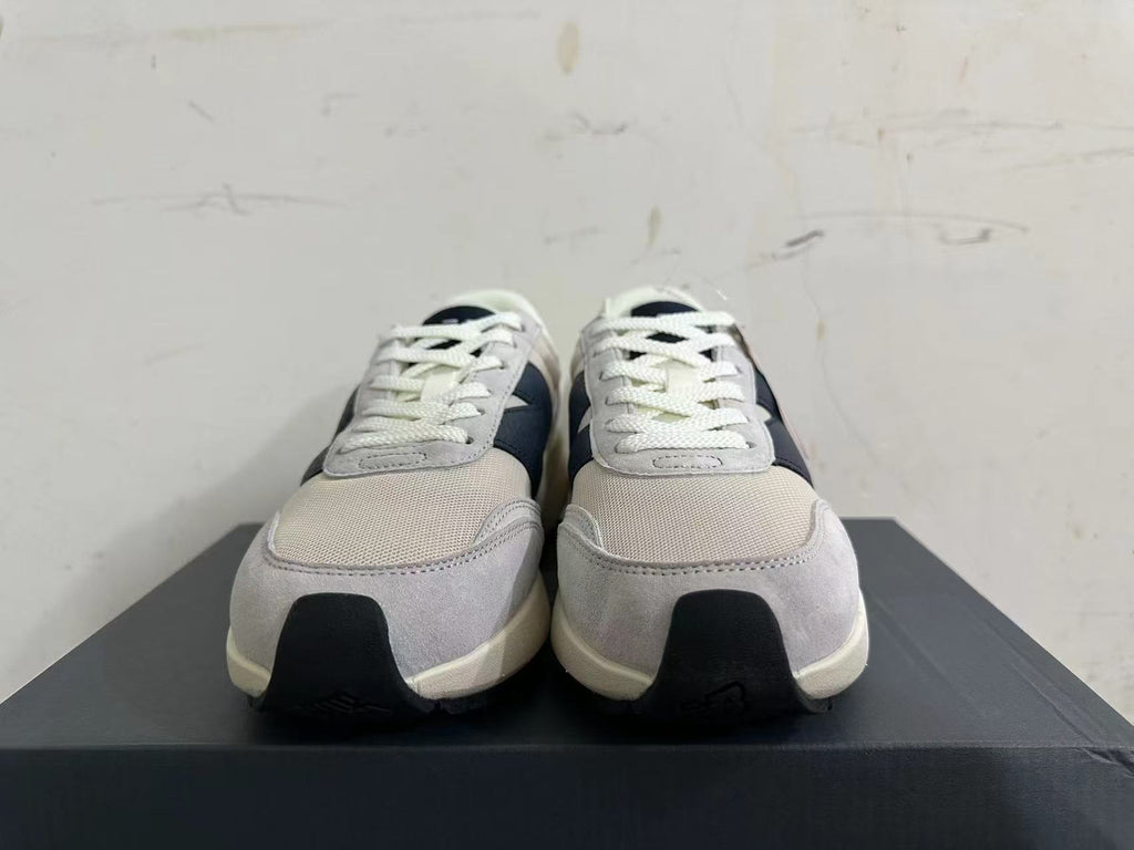 Front view of New Balance U370 sneakers showing white laces, gray panels, and navy details.