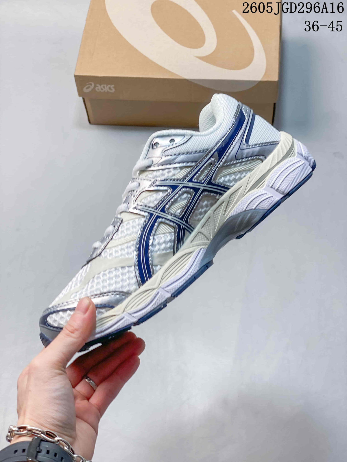 Side view of a white ASICS Gel-Cumulus 16 sneaker with silver overlays and navy detailing.