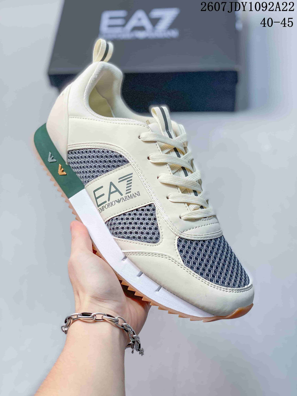 Close-up of a cream EA7 sneaker showing the side logo panel, dark textured inserts and lace-up front.