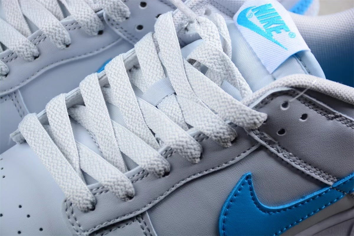 Close-up of the light gray and white sneaker upper showing woven laces, stitched panels, perforations, and a bright blue Swoosh.