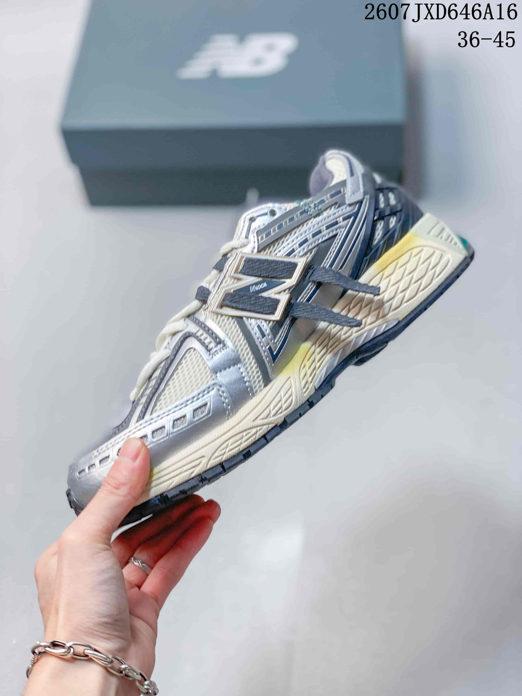 Side profile of a New Balance 1906A sneaker showing mesh panels, layered overlays, laces, and the segmented outsole.