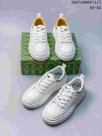 Multiple views of white Gucci sneakers arranged on and beside a green patterned box, showing the high-top silhouette and perforated toe panels.