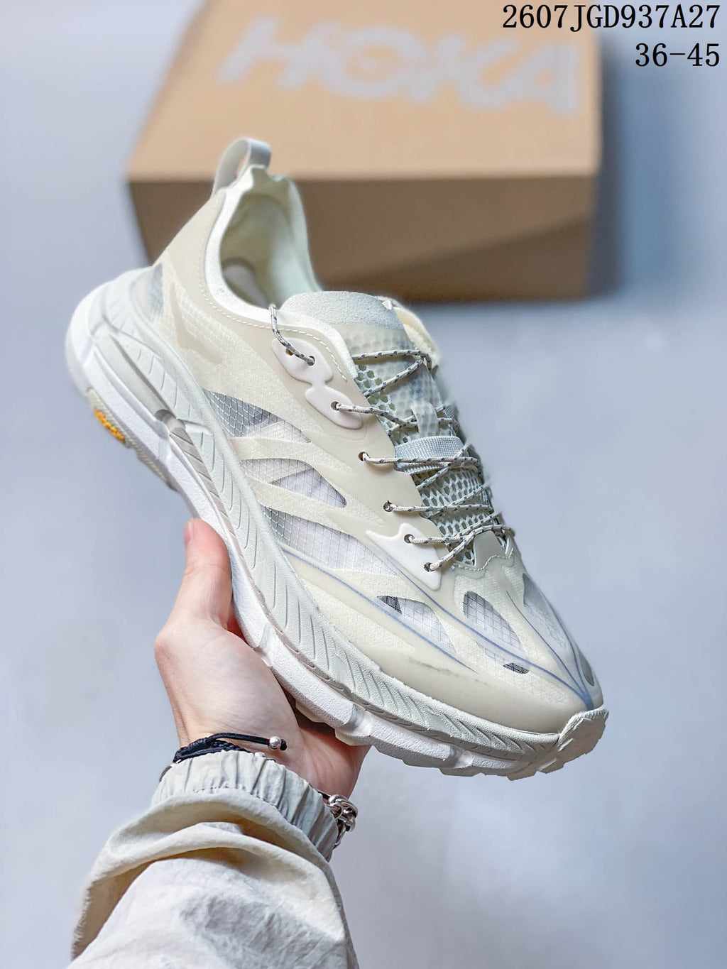 Angled side view of the white and light gray sneaker showing the lace system, layered panels, padded collar, and sole.
