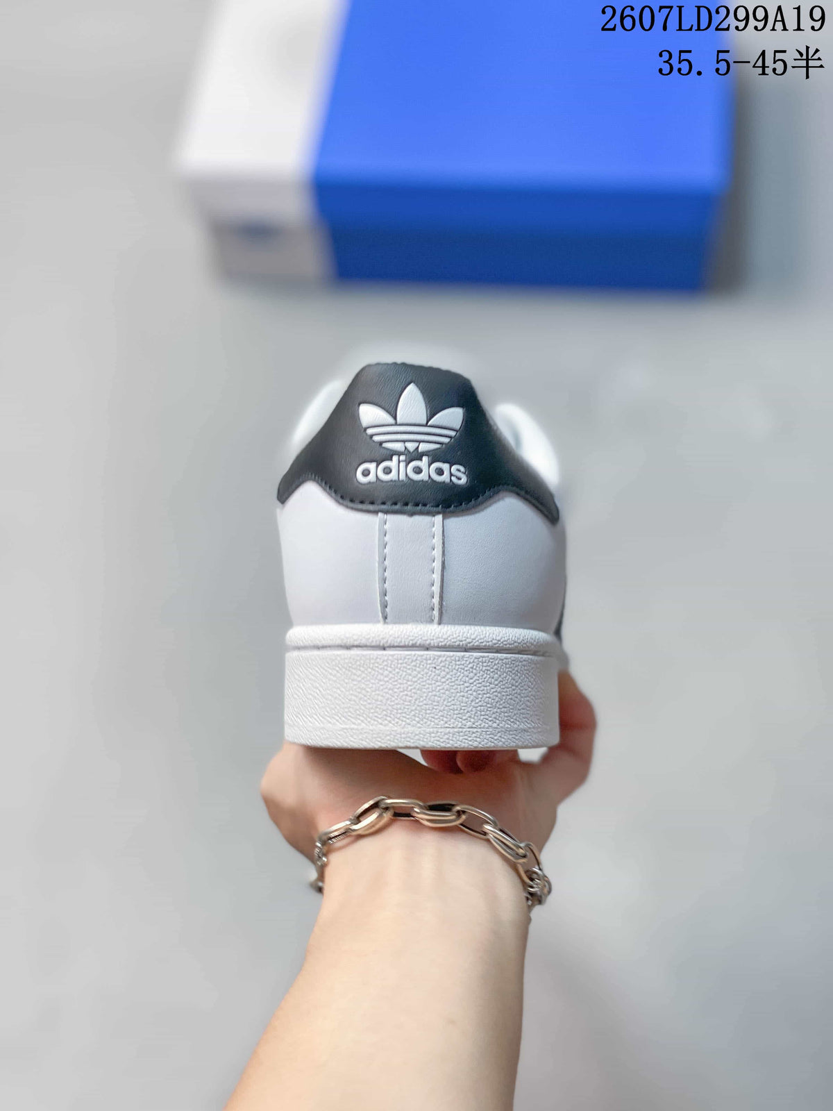 Rear view of a white adidas Superstar sneaker showing the black heel tab, Trefoil branding and white cupsole.
