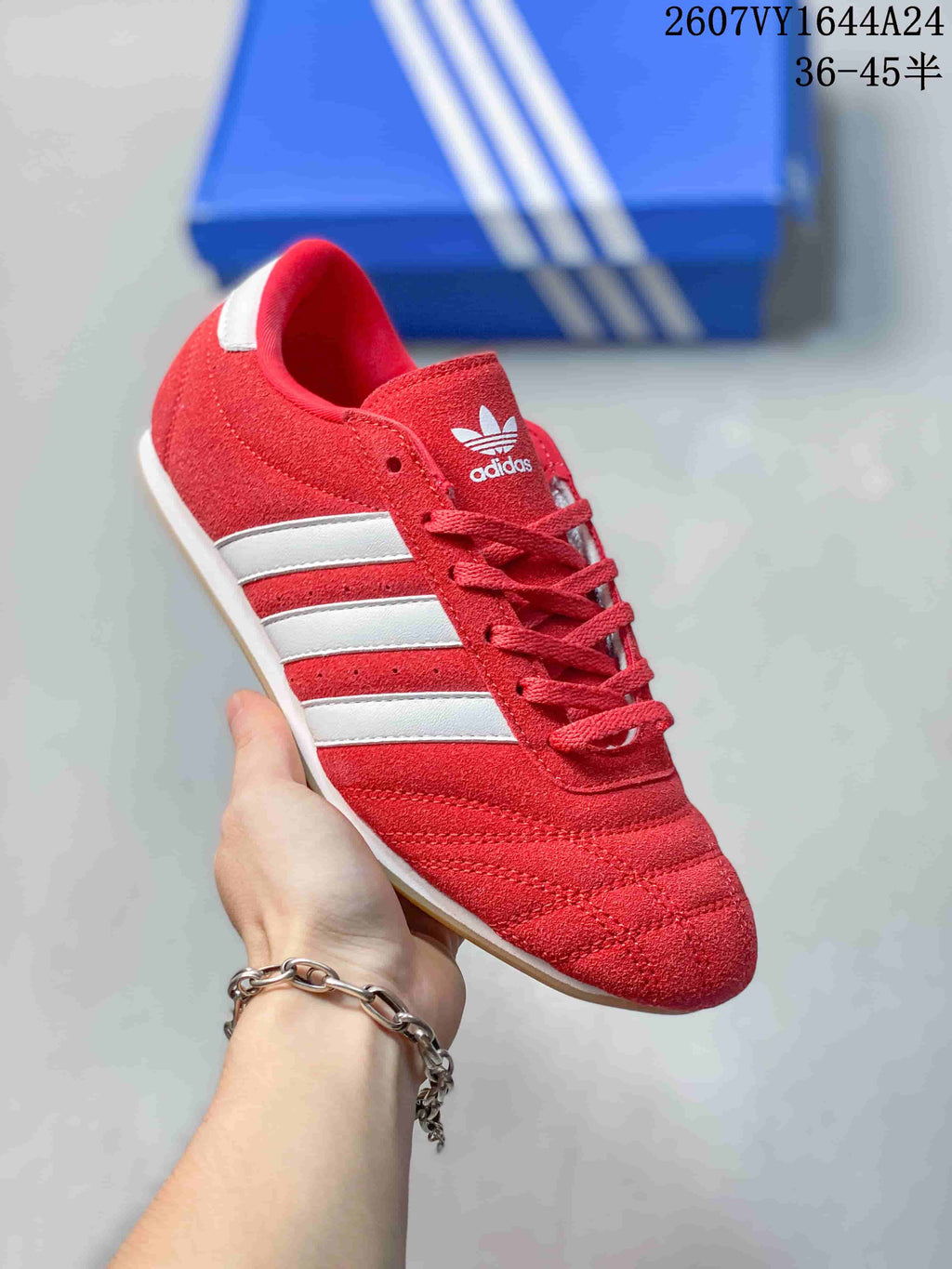 Angled side view of the red adidas Taekwondo sneaker with white stripes, red laces, and a gum-colored outsole.