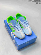 Pair of light blue and bright green adidas Tokyo sneakers displayed on a blue adidas shoe box.