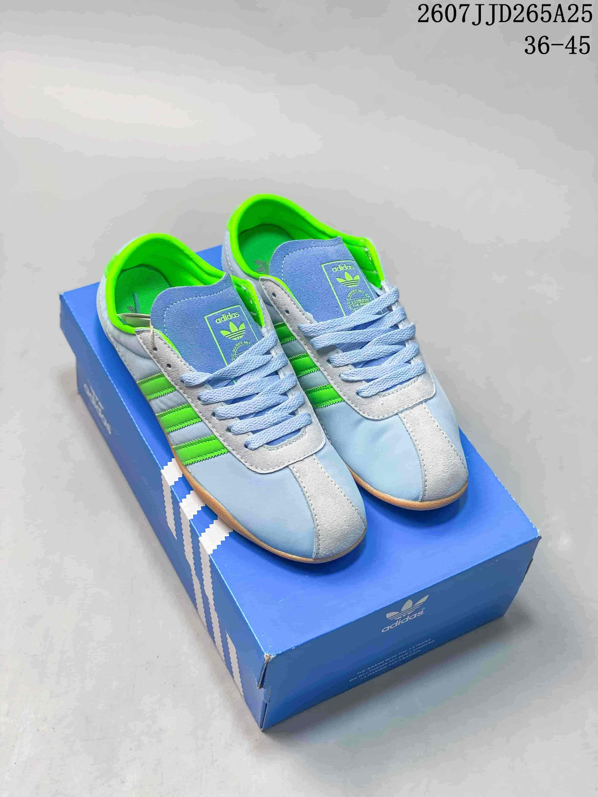 Pair of light blue and bright green adidas Tokyo sneakers displayed on a blue adidas shoe box.