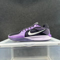Side view of a purple and black Nike sneaker with a visible Swoosh logo, patterned upper details, and a light-colored Air Zoom-marked midsole.