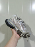 Angled view of a champagne and grey 3XL sneaker with layered panels, wide laces, and a dark outsole.