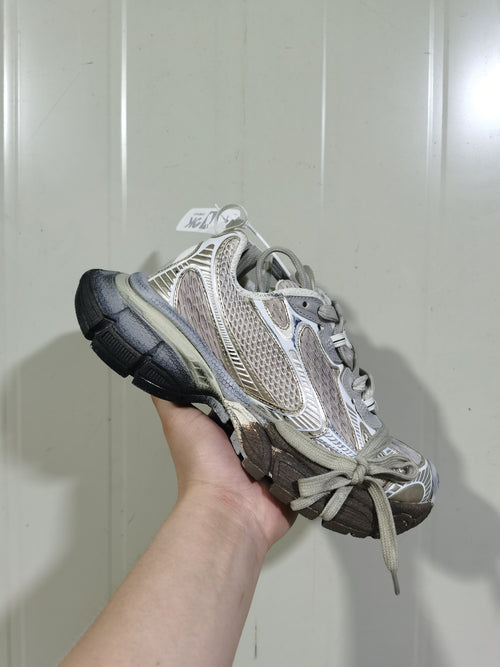 Angled view of a champagne and grey 3XL sneaker with layered panels, wide laces, and a dark outsole.