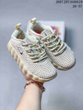 Pair of cream Nike Mind 002 kids' sneakers showing the perforated upper, laces, side Swoosh branding, and heel pull tabs.