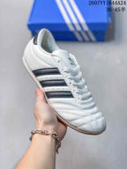 Angled side view of the white adidas Taekwondo sneaker with dark navy stripes, stitched upper panels, and gum-colored outsole.
