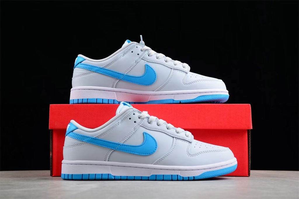 Side view of a sneaker positioned above a red shoebox, showing the bright blue Swoosh, gray and white upper, and blue outsole.