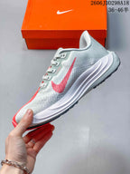 Side profile of the light grey running sneaker with a red Swoosh, white sculpted midsole, and black outsole edge.