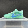 Side view of mint-jade green Nike low-top sneakers with blue accents and a sculpted sole.