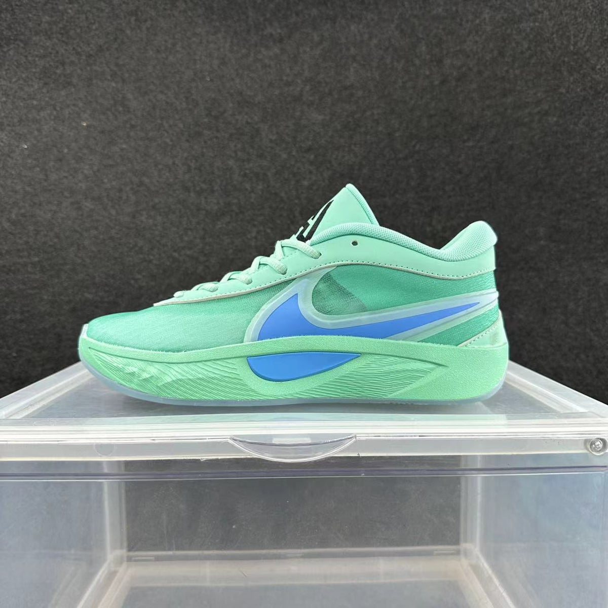 Side view of mint-jade green Nike low-top sneakers with blue accents and a sculpted sole.