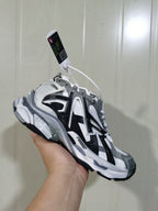 Angled view of the Balenciaga Runner sneaker showing the layered upper, side branding, chunky sole, and attached hangtag.