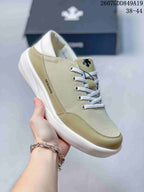 Close-up side view of a beige Descente sneaker showing the textured upper, contrasting toe panel, laces, side branding, and white sole.