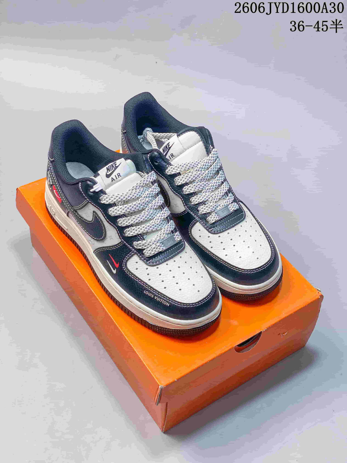 Pair of navy and white low-top sneakers with patterned panels and thick laces on an orange box