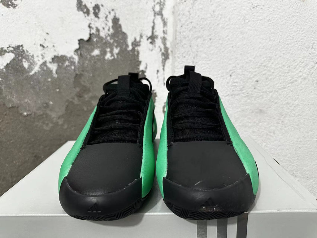 Front view of black and green Adidas basketball shoes with black laces.