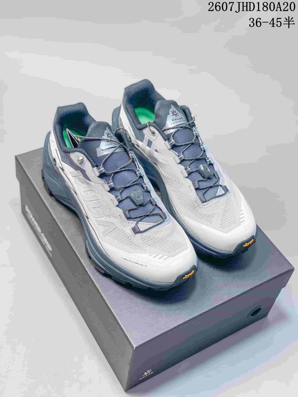 Pair of white, navy and gray Kailas low-top hiking shoes displayed on a shoebox; product code 2607JHD180A20 and size range 36–45 are visible.