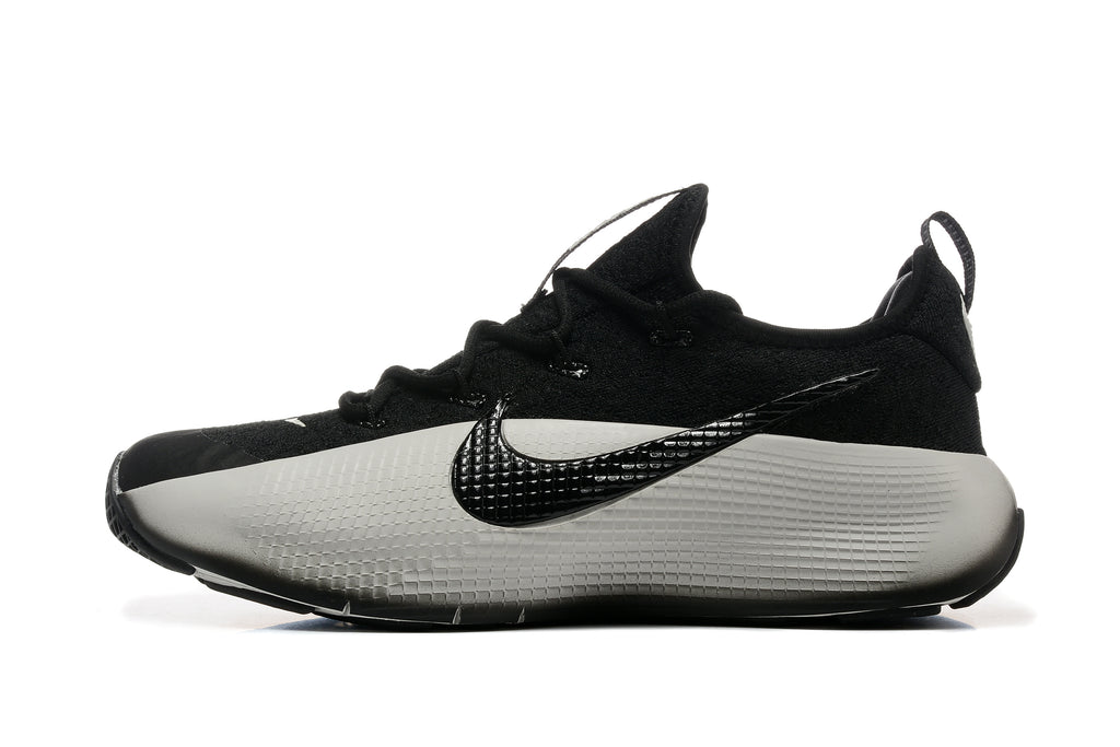Side profile of a black and white training shoe with a textured side panel and logo.
