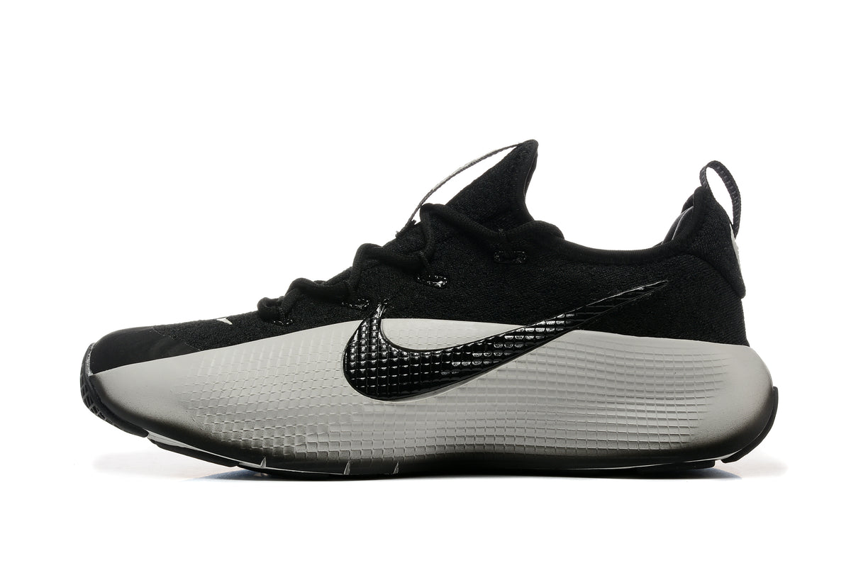 Side profile of a black and white training shoe with a textured side panel and logo.
