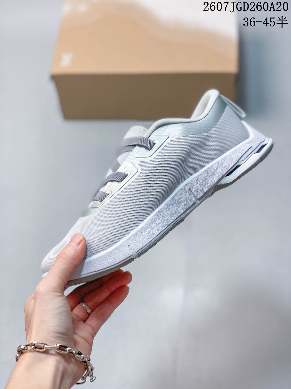Side view of the sneaker showing the streamlined upper, layered sole, and gray strap closure.