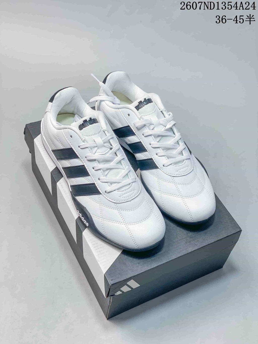 Pair of white and black adidas Adipista low-top sneakers displayed on a shoebox; image text shows style code 2607ND1354A24 and size range 36–45.5.
