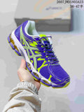 Purple and neon green ASICS Gel-Nimbus 16 sneaker held against a shoebox.