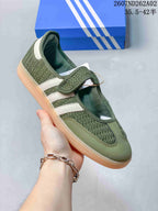 Angled side view of the olive-green sneaker with white stripes and hook-and-loop strap